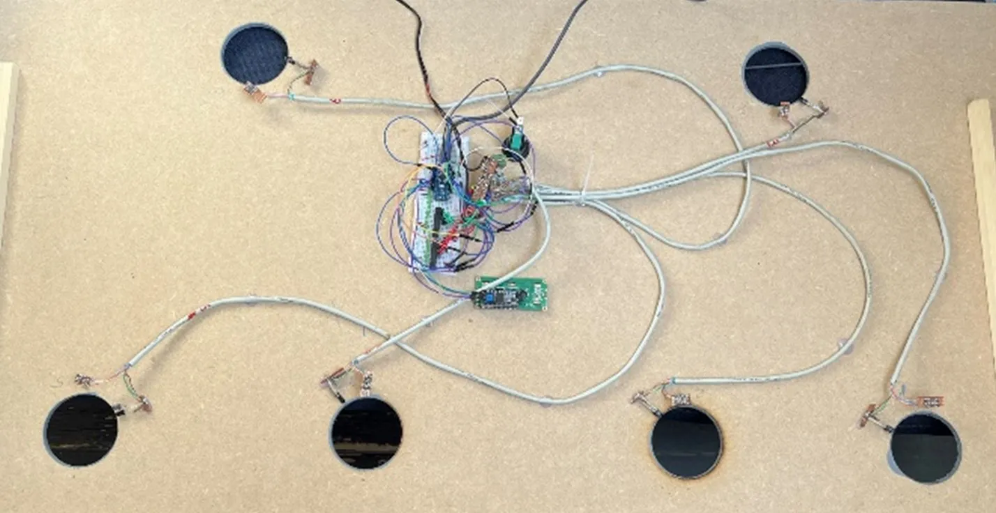 The underside of the top panel: six infrared emitter and detector pairs at the holes, wired back to an Arduino and expander boards taped to the centre of the MDF.