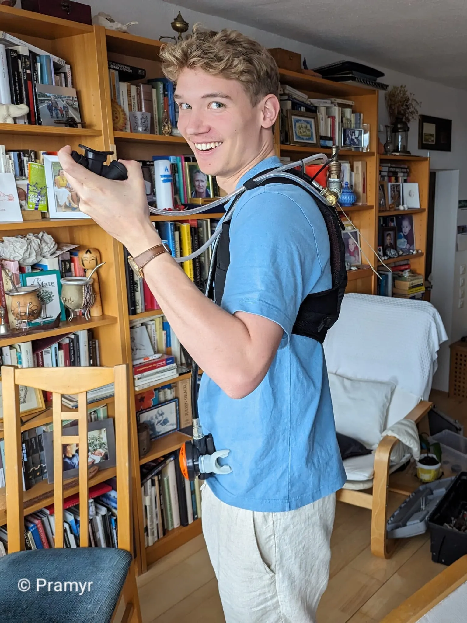 Lucas wearing the harness indoors, turned to camera and grinning, the airline running over his shoulder and a regulator held in one hand.