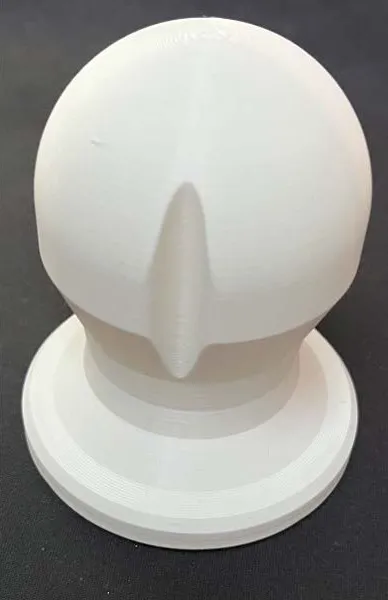 Close-up of the white 3D-printed controller: a domed top with a vertical indentation running down it, seated on a wide flat circular base.